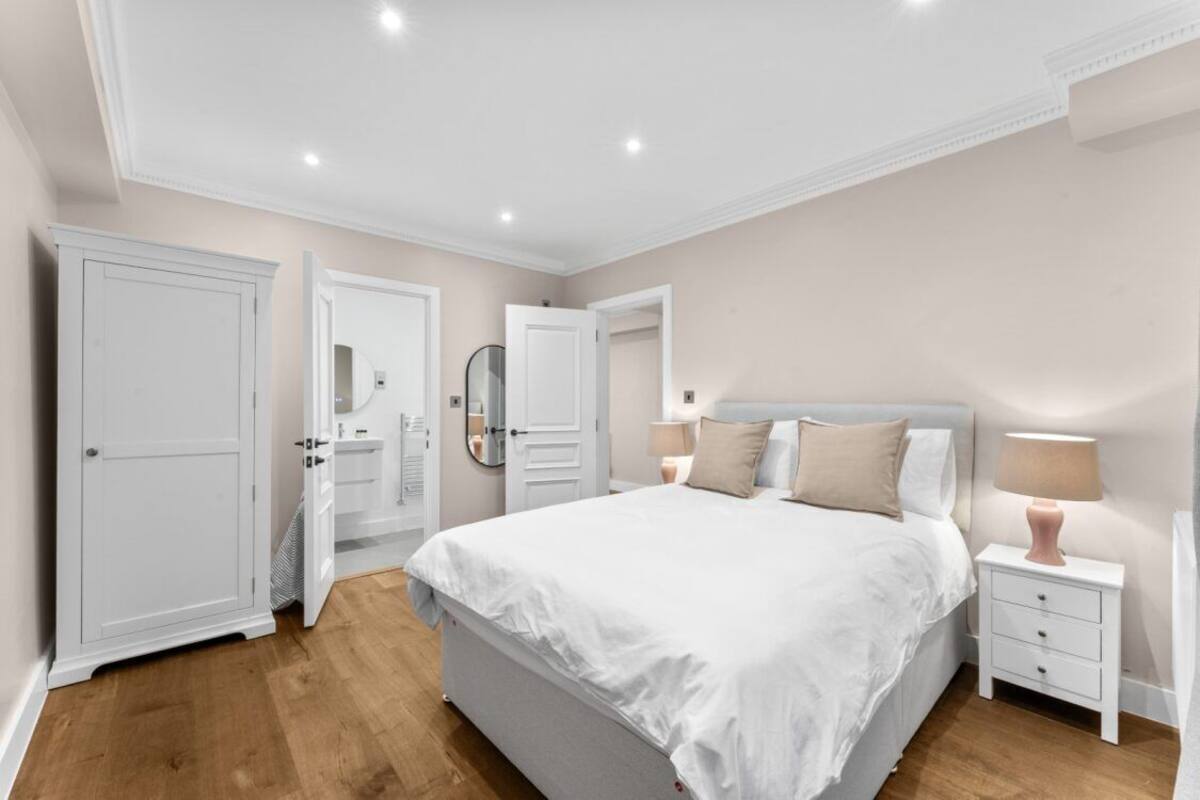 A bedroom with a large bed, bedside tables, a wardrobe, and a mirror.