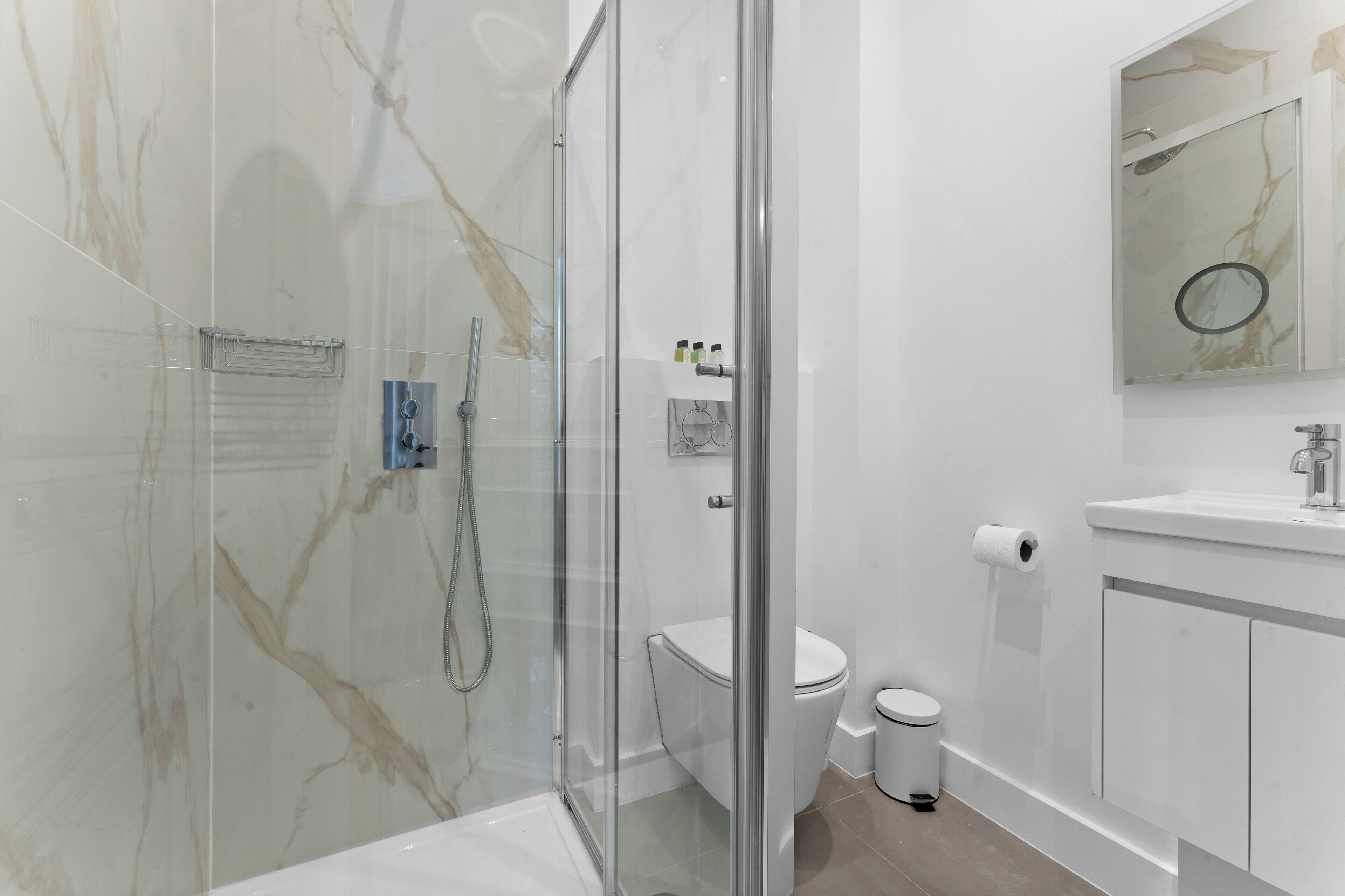 Een moderne badkamer met een douchecabine van glas, een toilet, een wastafel en een spiegel.
