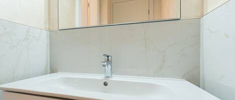 A bathroom with a white sink, a mirror above it, and marble-patterned walls.