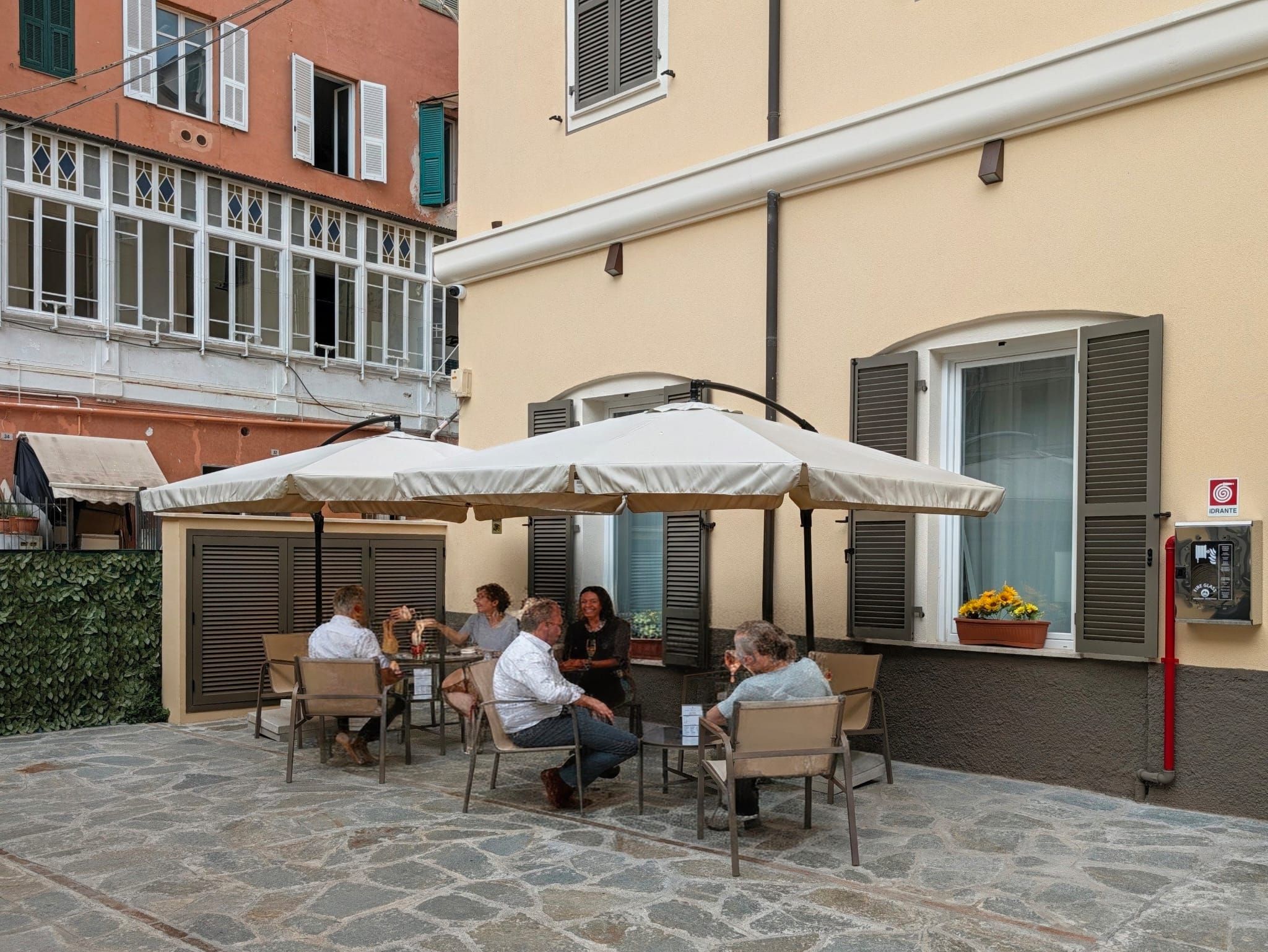 An outdoor patio with stone flooring, outdoor seating, and a covered area with umbrellas.