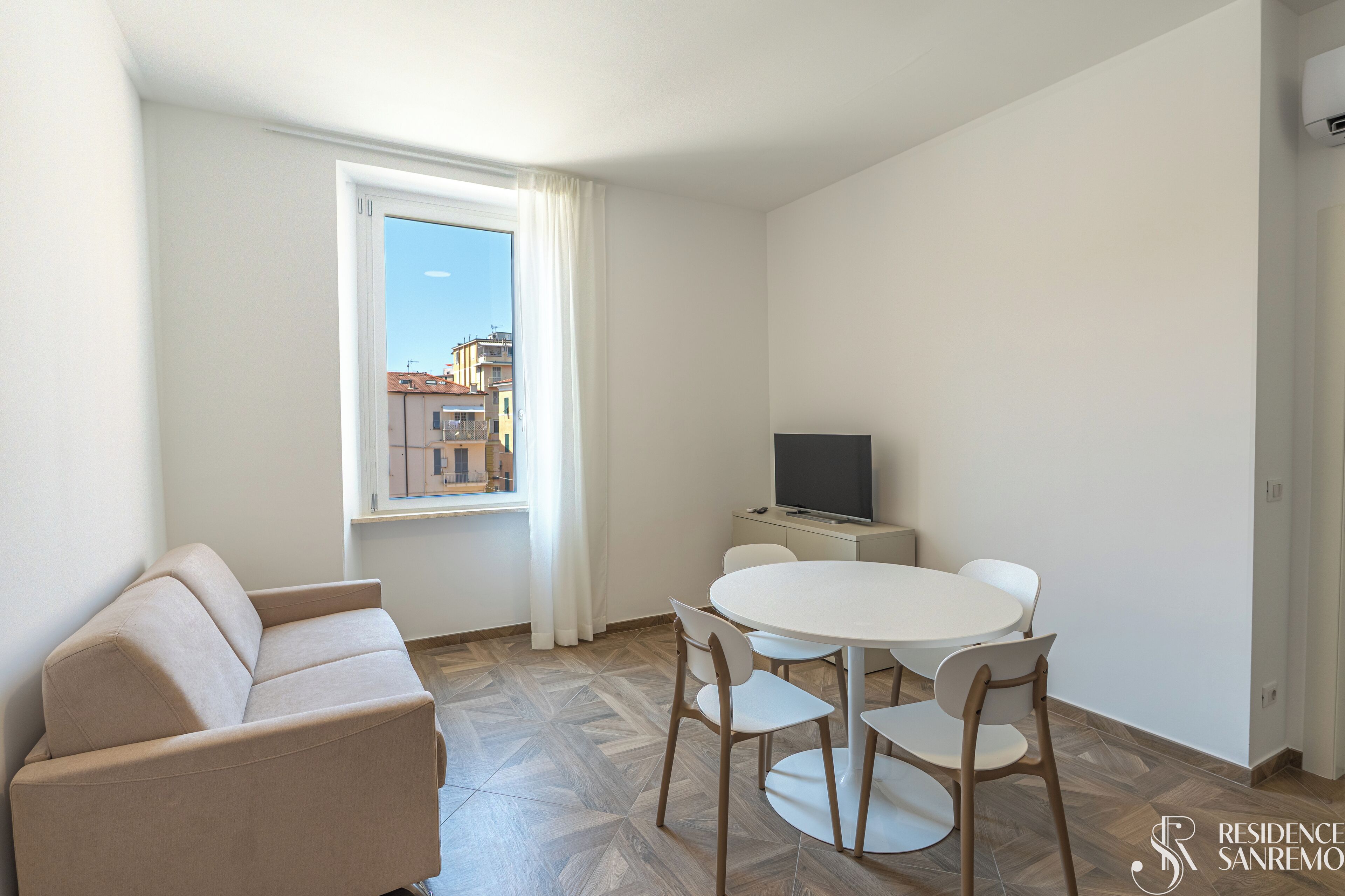 Un salon moderne comprenant un canapé, une table à manger avec des chaises, un téléviseur à écran plat et une fenêtre avec des rideaux.