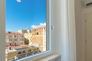 Una ventana con vistas a un paisaje urbano, que incluye edificios y un cielo despejado.