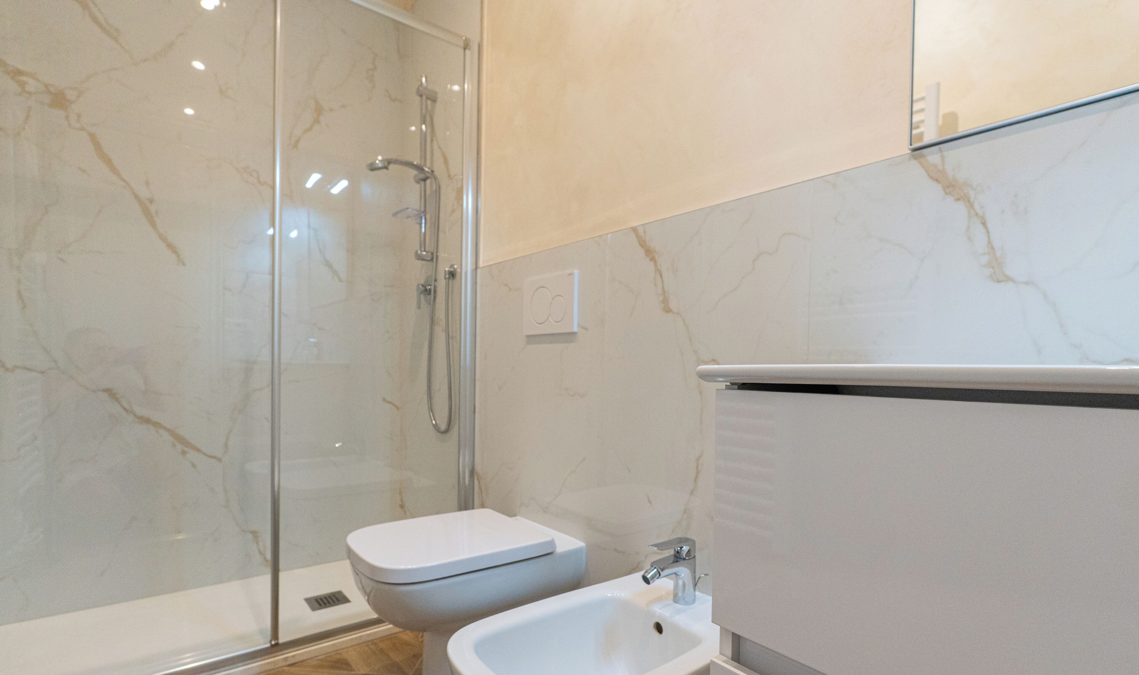 A modern bathroom with a glass shower enclosure, a toilet, and a sink.