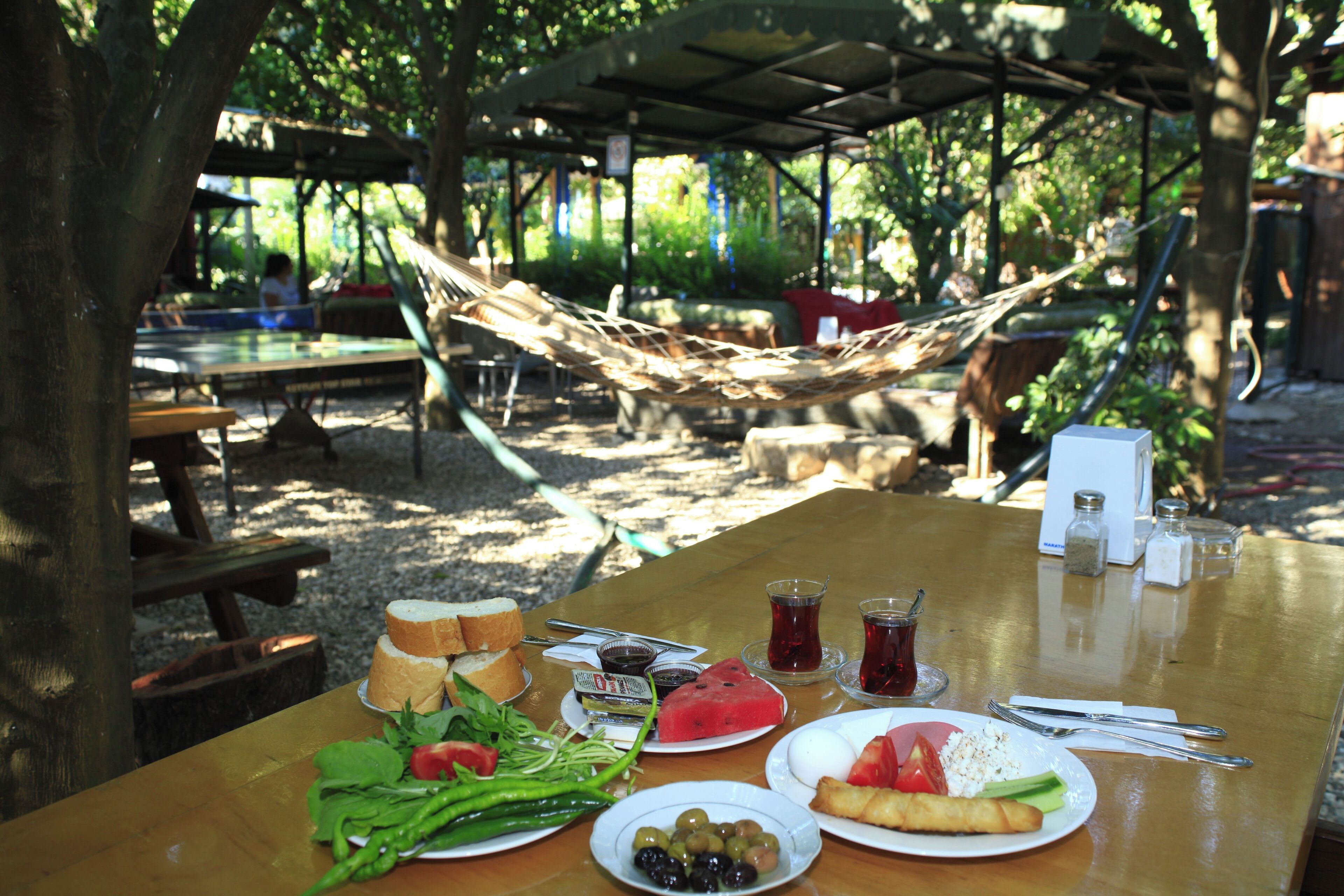 Une table de pique-nique avec de la nourriture, un hamac et un espace de repos abrité dans un parc.