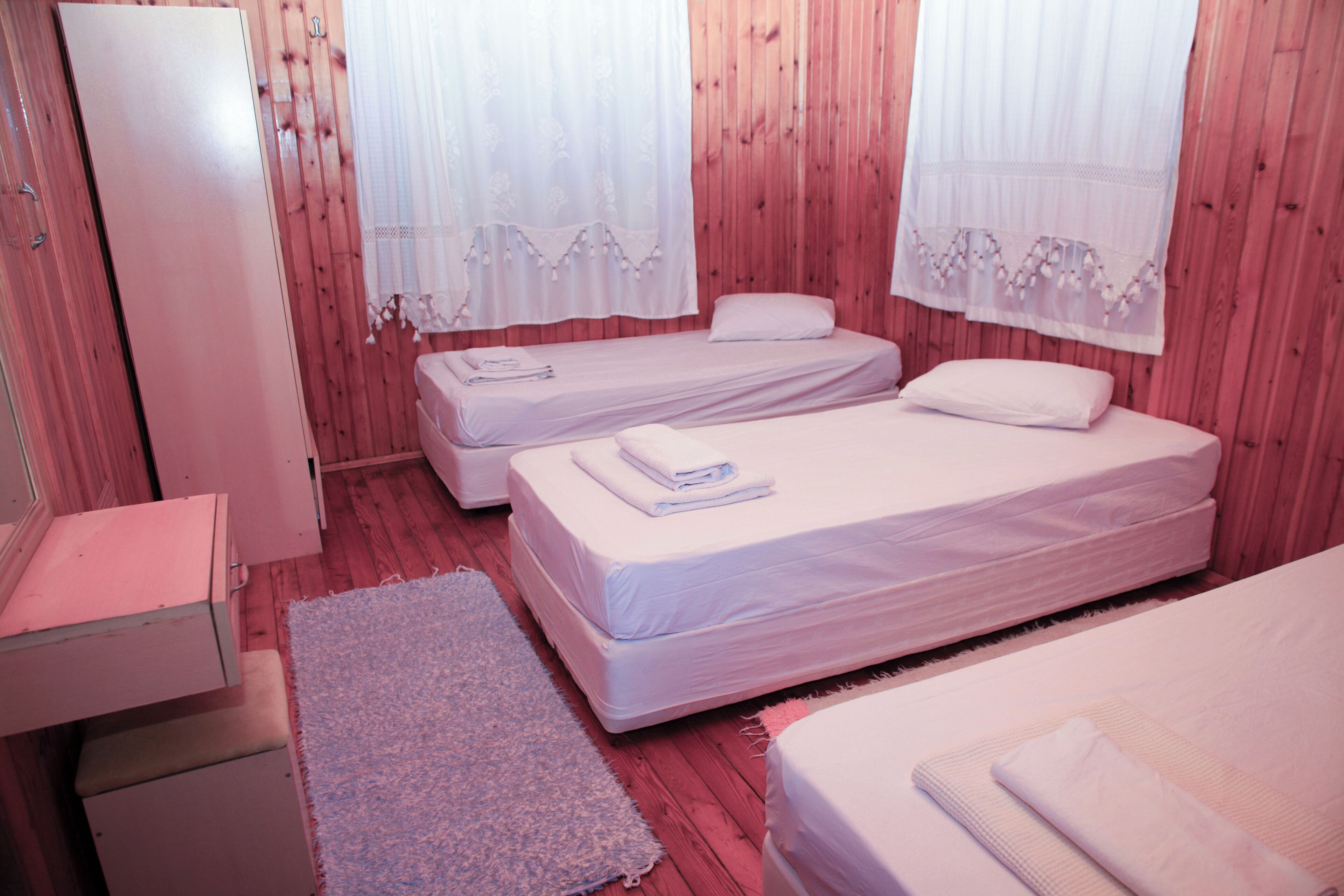 A room with two single beds, a small desk, and a wardrobe.