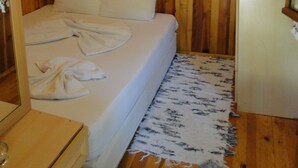 A wooden-paneled room with a bed, a white mattress, and a white blanket. - Korsan Pansiyon (Kumluca)