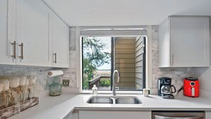 A kitchen with a large window, a sink, a coffee maker, and a toaster. - Marsh 2 the Beach, 2 Bedroom Island Rental (Saint Simons Island)