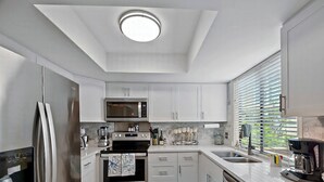 A modern kitchen with white cabinets, stainless steel appliances, and a skylight. - Marsh 2 the Beach, 2 Bedroom Island Rental (Saint Simons Island)