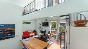 Un espace de vie moderne avec une table à manger en bois, un canapé rouge et un grand tableau accroché au mur.