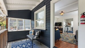 Un intérieur chaleureux aux murs bleu foncé, une terrasse en bois, un tapis à motifs bleus et un coin salon avec un fauteuil et des coussins.