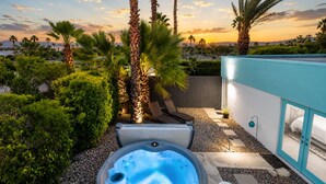 Un jacuzzi en un jardín con vistas a palmeras y un atardecer.