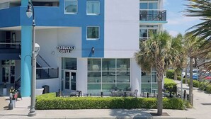 A multi-story building with a Starbucks Coffee sign, balconies, and a clear sky. - Boutique on the beach, Studio #106 + Pool (Myrtle Beach)