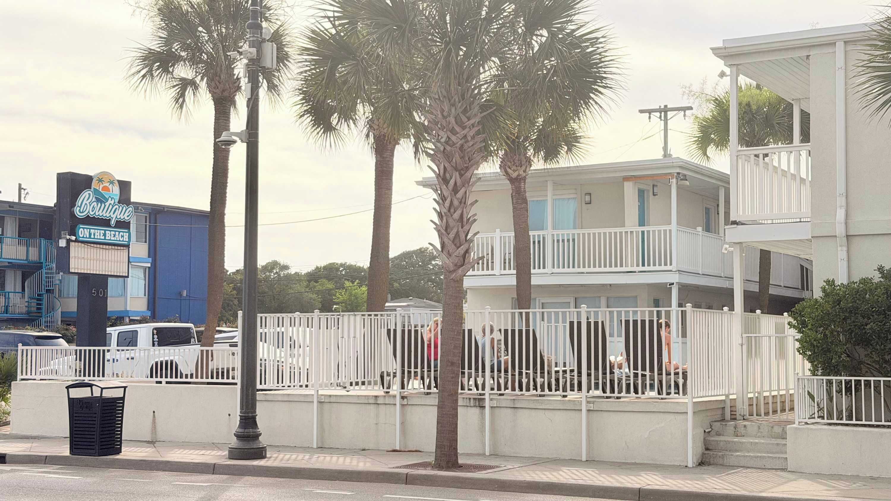 Un edificio de varios pisos con balcones, palmeras y un letrero para un hotel boutique.