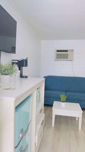 Ein modernes Wohnzimmer mit einem weißen Sofa, einem Couchtisch, einem Fernseher und einer Klimaanlage.