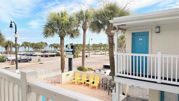 Ein Hotel direkt am Strand mit Balkon, Sitzgelegenheit im Freien und Palmen.