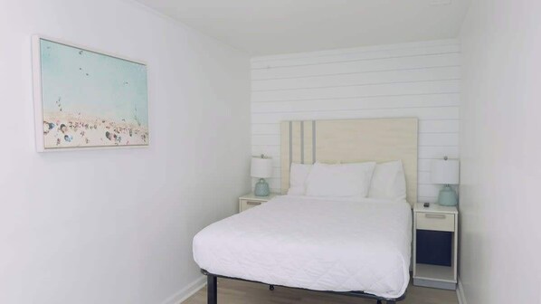 Une chambre à coucher comprenant un lit, deux tables de chevet, une commode et un tableau accroché au mur.