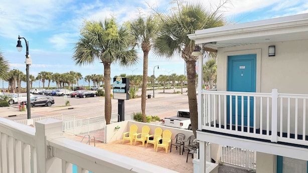 Une propriété située en bord de mer, dotée d’un balcon, d’un espace salon extérieur et offrant une vue sur la rue et l’océan.