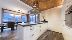 A modern kitchen with white cabinetry, a large island, and a view of mountains through the windows.