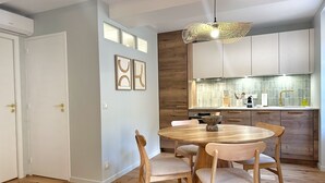 Et moderne køkken med træskabe, et rundt spisebord med stole og en hængende lampe.