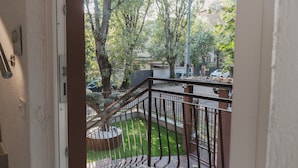 A view from a balcony with a metal railing, a small garden area, and a street with parked cars. - Residence I Tigli (Cinisello Balsamo)