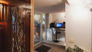 A modern interior with a glass door leading to a balcony, a desk with a computer, and a potted plant. - Residence I Tigli (Cinisello Balsamo)