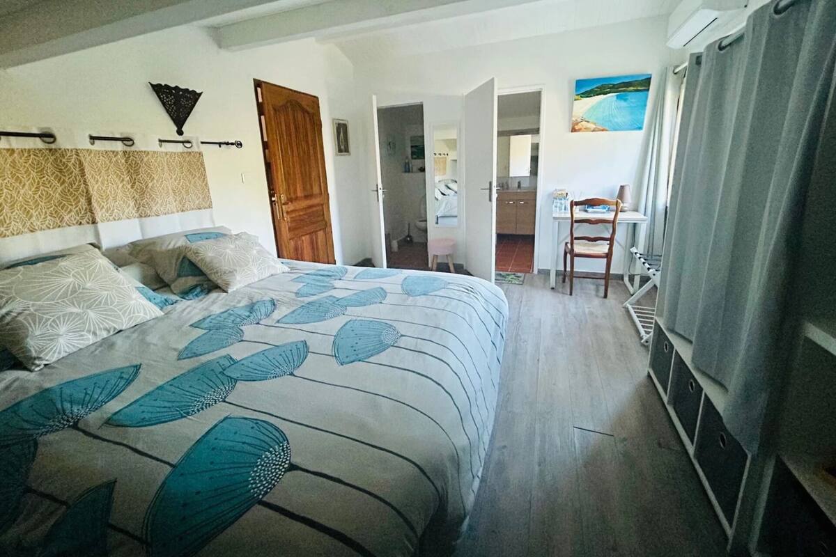 A bedroom with a bed, a desk, and a chair.