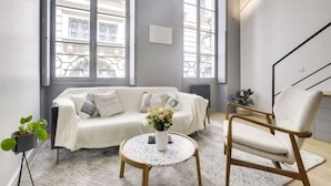 A modern living room with a white sofa, a round coffee table, and a chair. - Sun-filled Loft in the heart of the Marais (Paris)