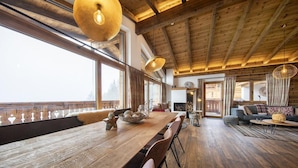 A spacious living area with a wooden dining table, sofas, and a fireplace. - Ski-friendly Chalet in Neukirchen (Neukirchen am Grossvenediger)