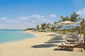 Plage privée, sable blanc, cabines (en supplément), chaises longues