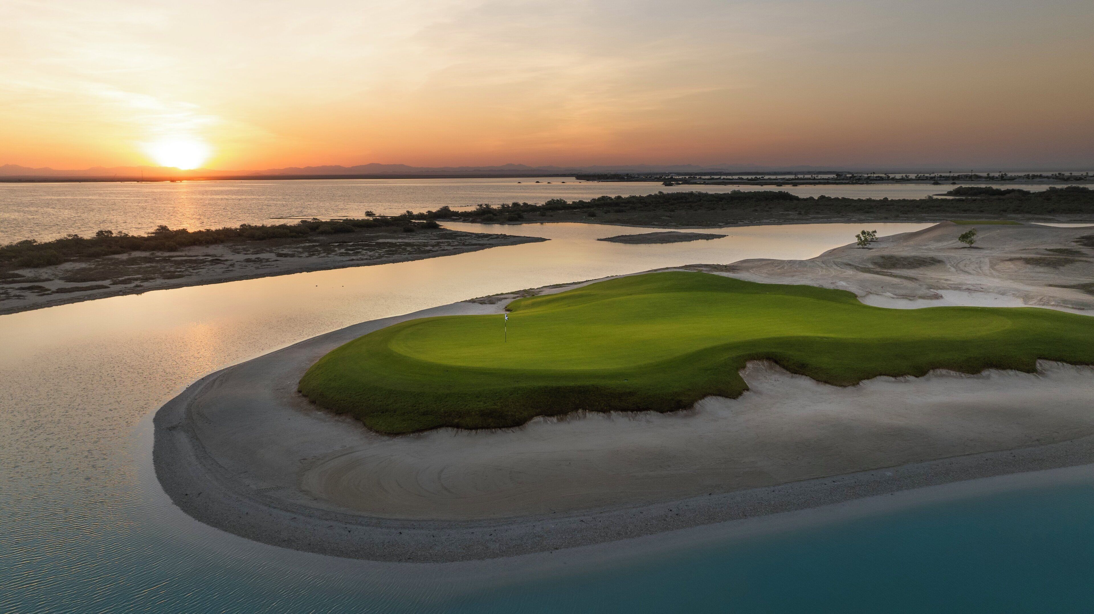Ein Golfplatz mit einem Wasserhindernis und Sanddünen.