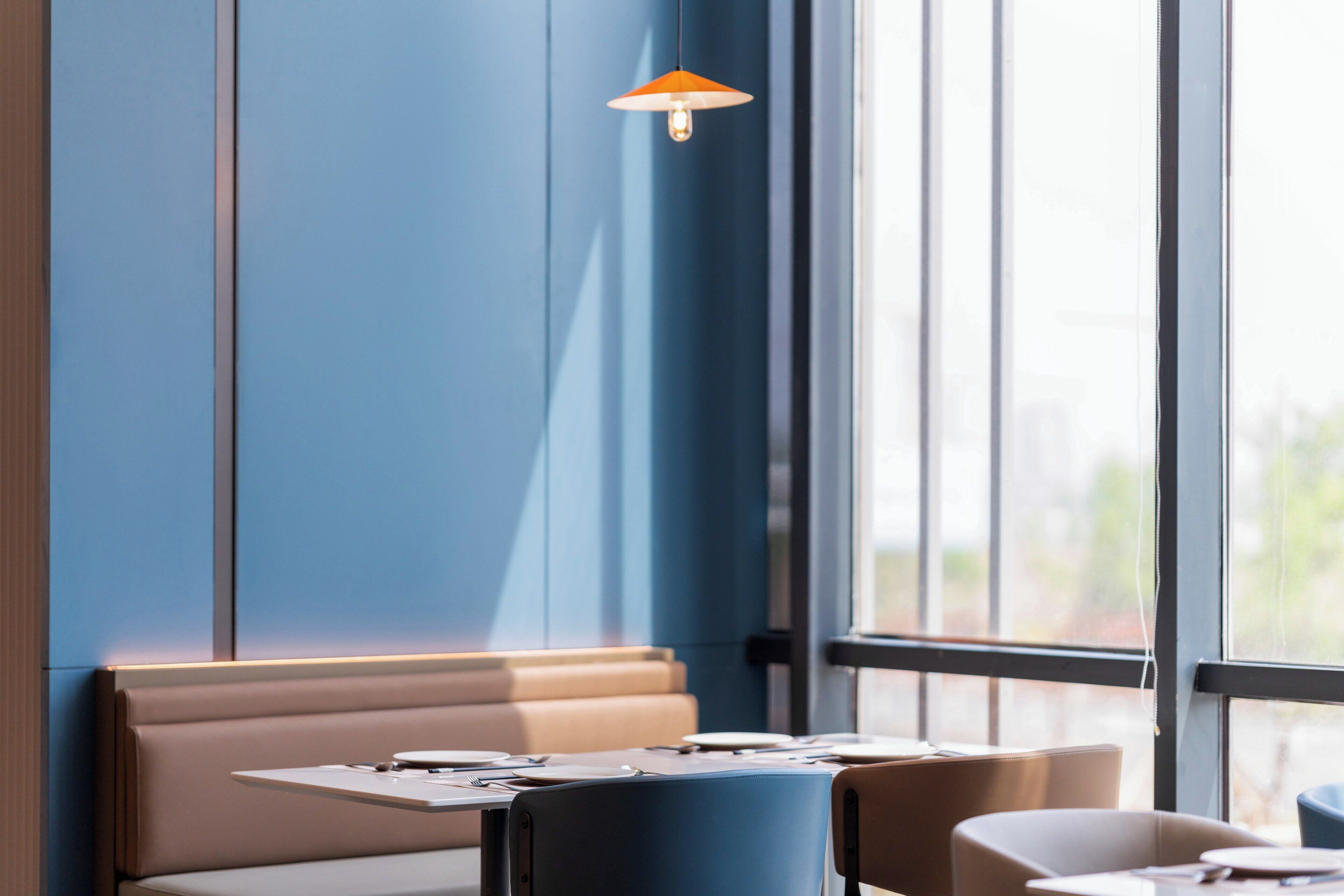 A modern interior with a blue accent wall, a table with a laptop, and a hanging lamp.