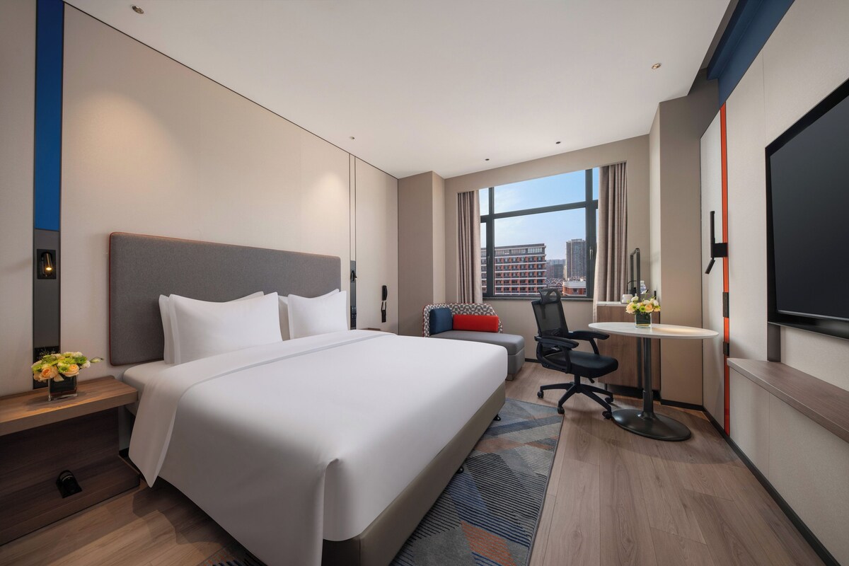 Une chambre d’hôtel moderne équipée d’un grand lit, d’un bureau, d’une chaise et d’une télévision.