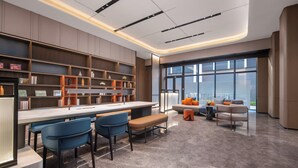Una cocina moderna con una isla central, taburetes de bar y una zona de estar con sofá y sillones.