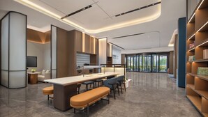 Un área de cocina moderna con una isla central, taburetes de bar y un rincón de estar con un banco.