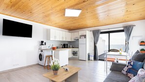 A modern apartment with a kitchen, dining area, and living room. It features wooden ceilings, a flat-screen TV, a sofa, and a dining table. - Home2Book Peaceful Apt & Sea View Terrace in Arico (Arico)