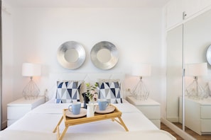 A hotel room with a bed, bedside tables, a tray with cups and a pitcher, decorative pillows, and wall mirrors. - Home2Book Dreamy View Of The Bay & Private Terrace (Tabaiba)