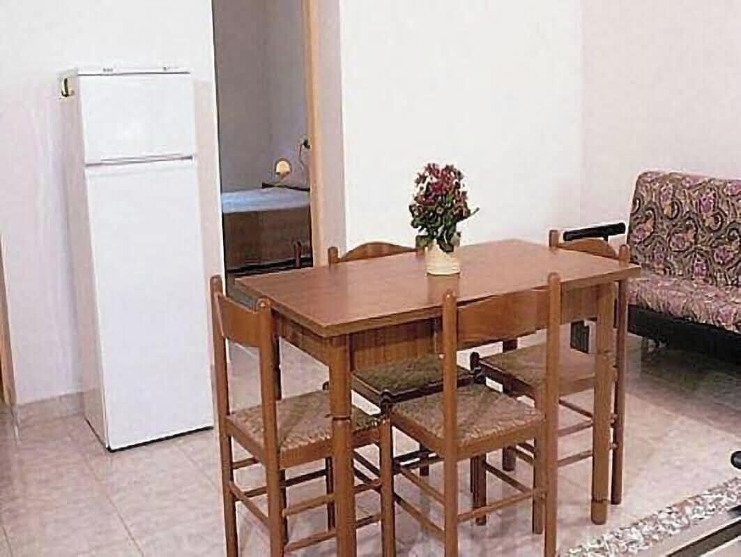 Un comedor con una mesa y sillas de madera, un refrigerador blanco y un sofá estampado.