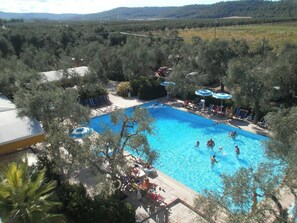 A swimming pool surrounded by trees, with people swimming and sunbathing. - Residence Baia Del Gallo (Vieste)