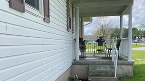 A house with a covered porch, steps leading up to it, and a garden with various plants and flowers.