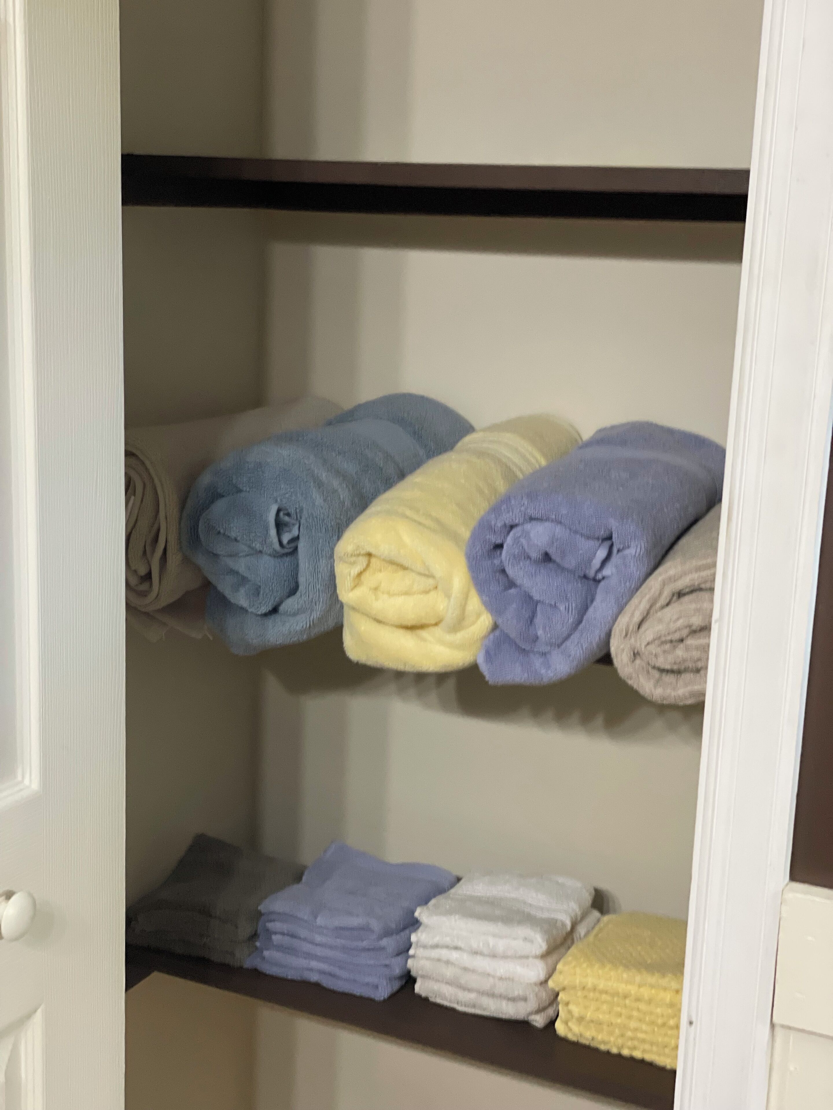 Un espace de rangement doté d’étagères où sont pliées des serviettes de différentes couleurs.