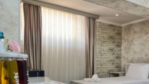 A hotel room with a marble countertop, two beds, a brick accent wall, and a large window with curtains. - Ammar hotel (Tashkent)