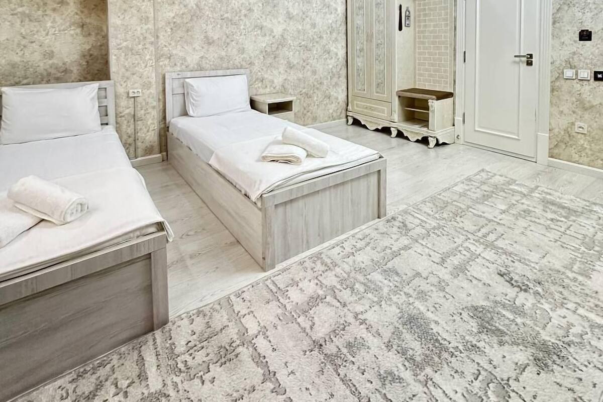 A modern bedroom with two beds, a walk-in closet, and a marble-patterned wall.