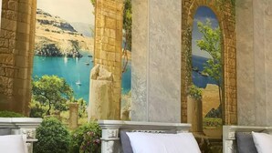 A hotel room with a mural of a coastal landscape, two beds, and a small table. - Ammar hotel (Tashkent)