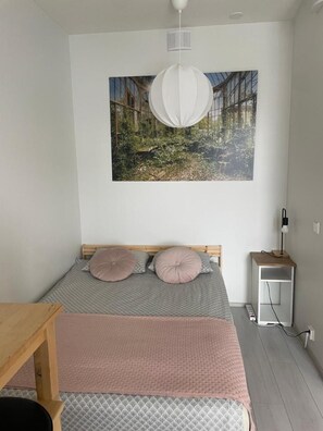 A bedroom with a bed, a bedside table, a lamp, and a wall-mounted picture. - Charming 1-bedroom Apartment in Tampere With Fireplace (Tampere)