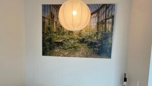 A bedroom with a bed, a bedside table with a lamp, and a large wall-mounted picture. - Charming 1-bedroom Apartment in Tampere With Fireplace (Tampere)