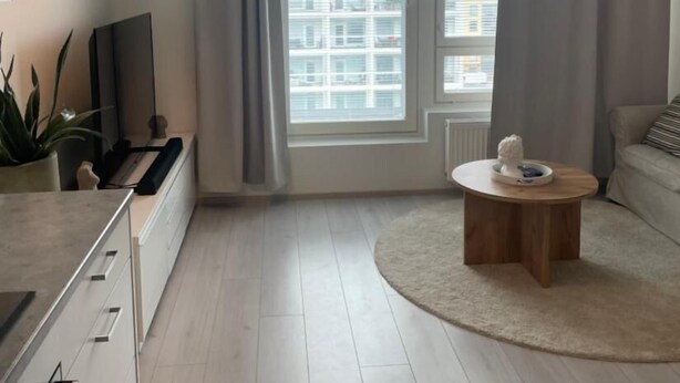A modern living room with a large window, a round coffee table, and a minimalist design. - Charming 1-bedroom Apartment in Tampere With Fireplace (Tampere)