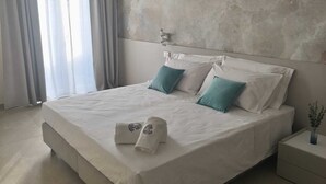 Een moderne slaapkamer met een groot bed, een structuurwand en een nachtkastje met een vaas.