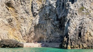 Helder turquoise water met rotsachtige kliffen en een klein strand.