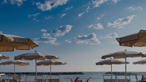Een strandsetting met meerdere parasols en ligstoelen.