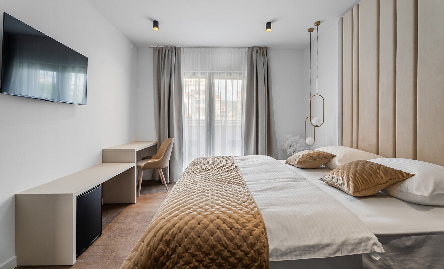 Una habitación de hotel moderna con una cama, un escritorio y un televisor.